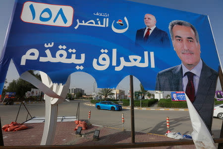 Vehicles drive near a campaign banner of candidates ahead of parliamentary election, in Najaf, Iraq, April 20, 2018. REUTERS/Alaa Al-Marjani