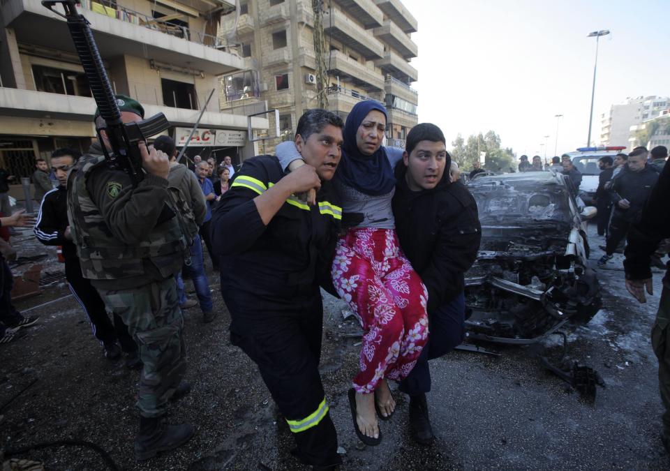 Civil defence members carry a wounded woman as a Lebanese Army soldier secures the area at the site of an explosion in the southern suburbs of Beirut February 19, 2014. The explosion on Wednesday appeared to be caused by a twin bomb attack using a car and a motorcycle, security sources said. (REUTERS/Mahmoud Kheir)