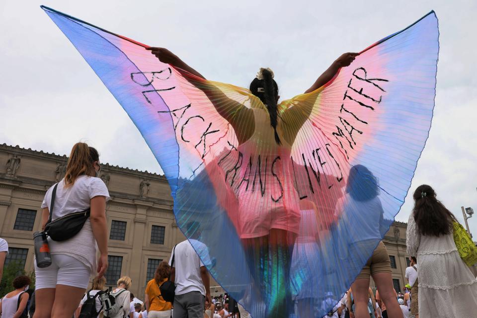 A person spreads wings with the words "Black Trans Lives Matter" written on them during the Brooklyn Liberation's Protect Trans Youth event at the Brooklyn Museum on June 13, 2021, in the Brooklyn borough in New York City. Brooklyn Liberation organized a march and rally as an emergency action response to legislation to restrict trans rights across 34 states.