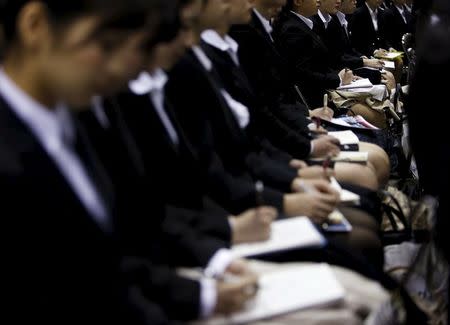 Female job seekers take notes as they attend an orientation session at a company booth during a job fair held for fresh graduates in Tokyo, Japan, March 20, 2016. REUTERS/Yuya Shino/Files