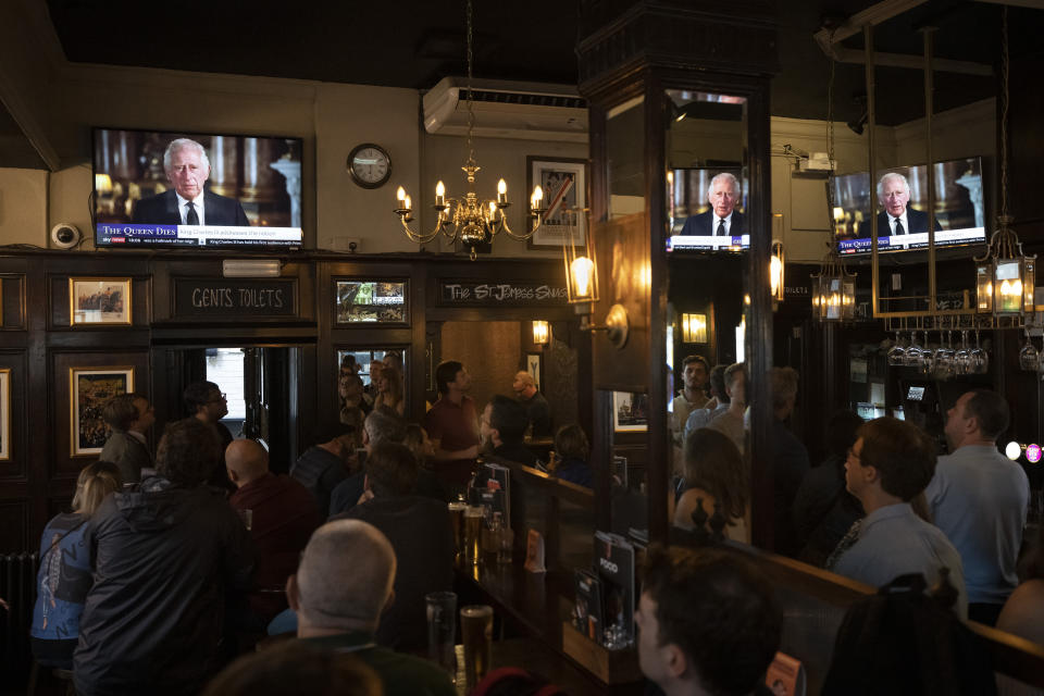 People watch a broadcast of Britain's King Charles III first address to the nation as the new King following the death of Queen Elizabeth II, in London, Sept. 9, 2022. (AP Photo/Felipe Dana)