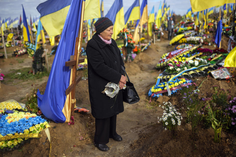 Olga stands next to the grave of a relative recently killed on military duty, in a cemetery, during Ukraine Defenders Day in Kharkiv, Ukraine, Friday, Oct. 14, 2022. (AP Photo/Francisco Seco)