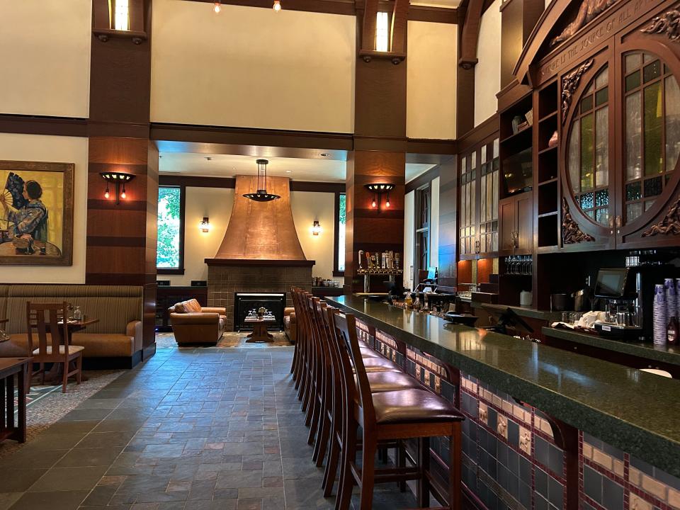 The interior of a bar with dark-wood chairs, a fireplace, and couches.