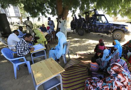 Special Prosecutor for Crimes in Darfur Yasir Ahmed Mohamed (back, in blue shirt with glasses) and his team talk to women during an investigation into allegations of mass rape in the village of Tabit, in North Darfur, November 20, 2014. REUTERS/Mohamed Nureldin Abdallah