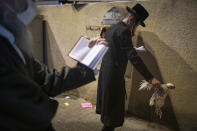 An ultra-Orthodox Jewish man holds a chicken as part of the Kaparot ritual, in Bnei Brak, Israel, Sunday, Sept. 27, 2020. Observant Jews believe the ritual transfers one's sins from the past year into the chicken, and is performed before the Day of Atonement, Yom Kippur, the holiest day in the Jewish year which starts at sundown Sunday. The solemn Jewish holiday of Yom Kippur, which annually sees Israeli life grind to a halt, arrived on Sunday in a nation already under a sweeping coronavirus lockdown. (AP Photo/Oded Balilty)