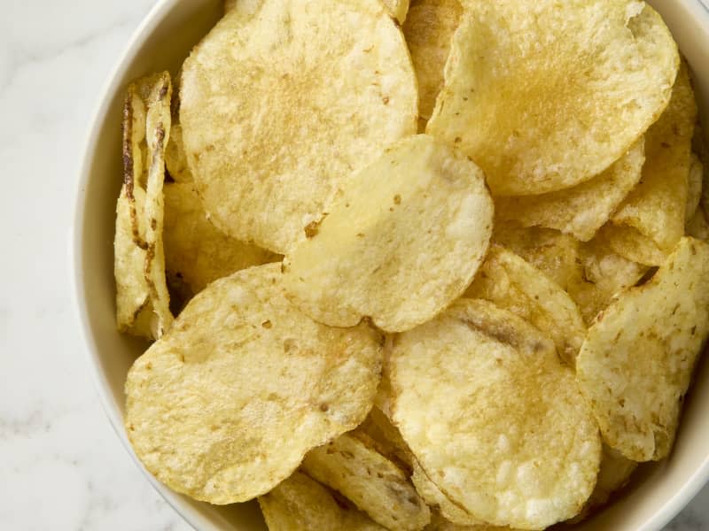 overhead shot of potato chips in a beige bowl