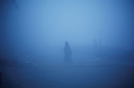 A woman walks on the banks of Yamuna river on a foggy winter morning in New Delhi, India, December 24, 2018. REUTERS/Adnan Abidi