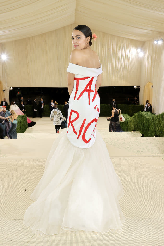 Alexandria Ocasio-Cortez at an event wearing a gown with 'TAX THE RICH' in bold letters