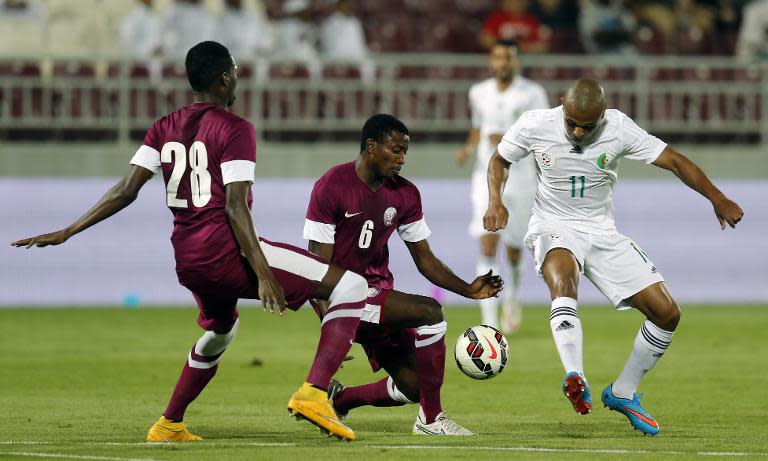 Qatar's Abdulrahman Abakar (L) and Kasola Mohamed (C) defend against Algeria's Yacine Brahimi (R) during their friendly football match in Doha on March 26, 2015