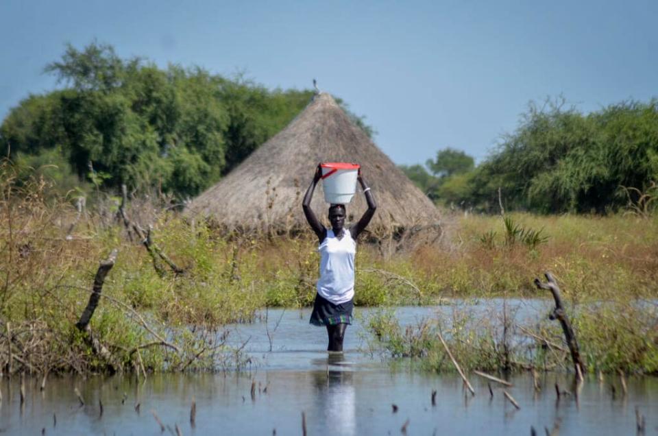 A woman wades through floodwaters in the village of Wang Chot, Old Fangak county, Jonglei state. South Sudan President Salva Kiir Mayardit ordered the suspension on Saturday, July 9, 2022 of all dredging-related activities in the country until evidence-based studies are carried out on their impact on surrounding communities and ecosystems. (AP Photo/Maura Ajak, File)