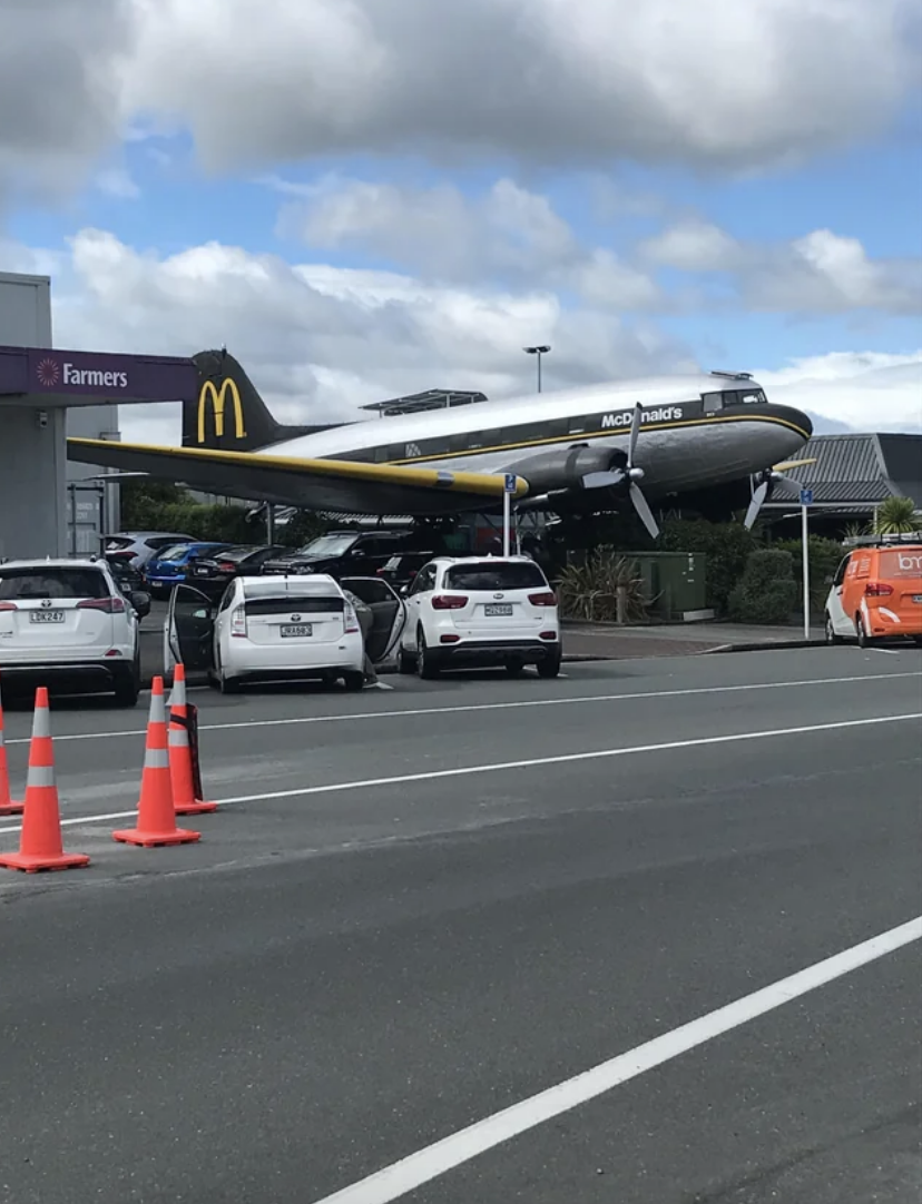 Airplane-shaped McDonald's restaurant above parked cars at a unique dining location