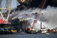 Fire fighters spray water into the cut away mid-section of the cargo vessel Golden Ray, Friday, May 14, 2021, Brunswick, Ga. The Golden Ray had roughly 4,200 vehicles in its cargo decks when it capsized off St. Simons Island on Sept. 8, 2019. Crews have used a giant gantry crane to carve the ship into eight giant chunks, then carry each section away by barge. (AP Photo/Stephen B. Morton)