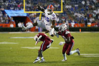 Florida quarterback Anthony Richardson (15) hurdles Florida Atlantic defensive back Justin McKithen (11) and safety Armani-Eli Adams (30) during the second half of an NCAA college football game Saturday, Sept. 4, 2021, in Gainesville, Fla. (AP Photo/John Raoux)