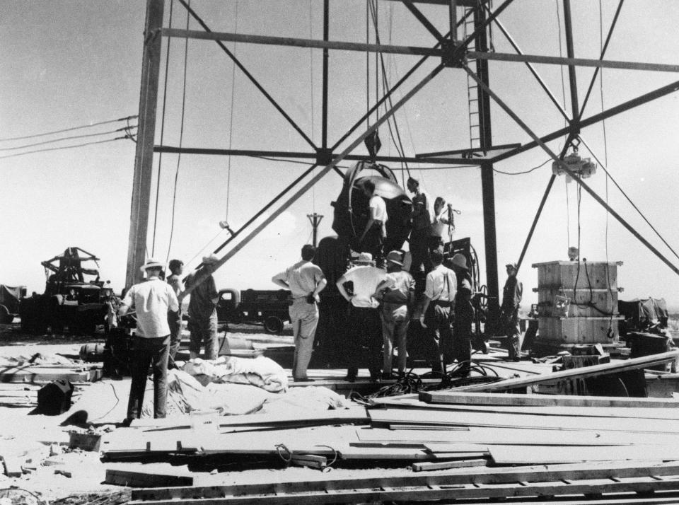 FILE - Scientists and other workers rig the world's first atomic bomb to raise it up onto a 100-foot tower at the Trinity Test Site near Alamagordo, N.M. A new film on J. Robert Oppenheimer's life and his role in the development of the atomic bomb as part of the Manhattan Project during World War II opens in theaters on Friday, July 21, 2023. On the sidelines will be a community downwind from the testing site in the southern New Mexico desert, the impacts of which the U.S. government never has fully acknowledged. (AP Photo/File )