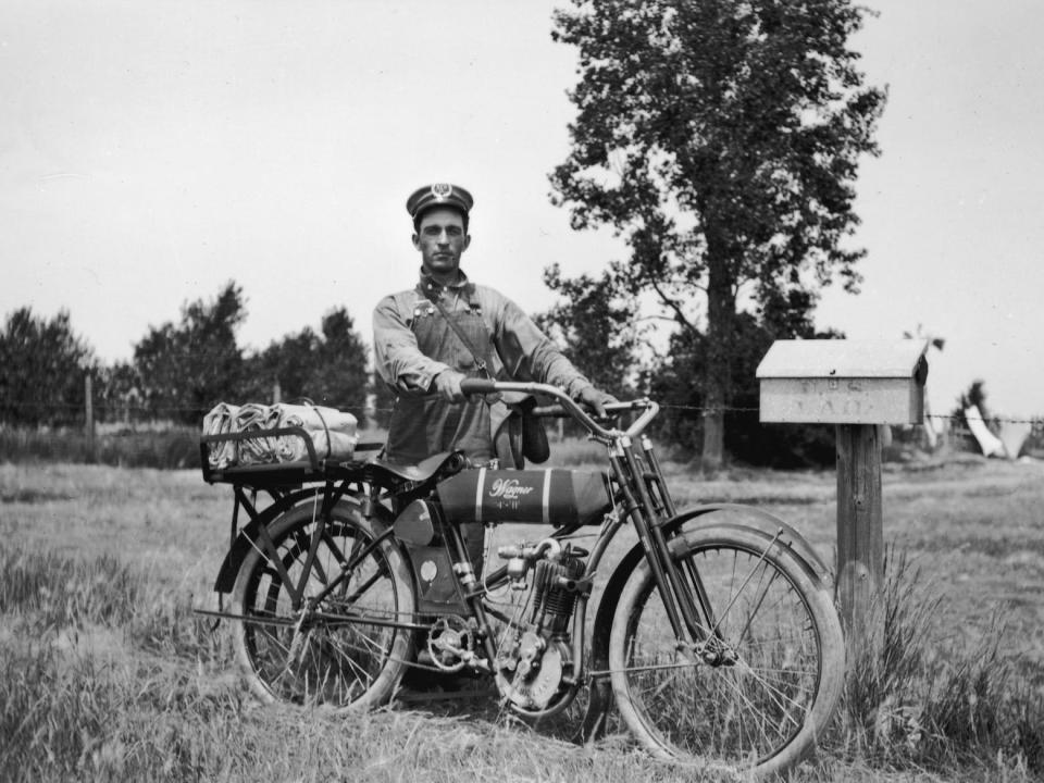 A postal worker rides a motorcycle