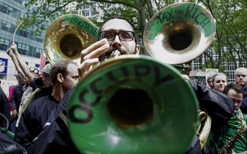 Trumpeter Andrew Morton, a member of the Rude Mechanical Orchestra from Brooklyn, N.Y.,  performs with the group as protesters gather at Bryant Park to prepare for a May Day march on Tuesday, May 1, 2012 in New York. (AP Photo/Bebeto Matthews)