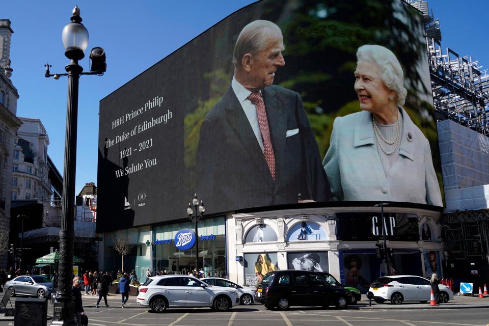 Images of the queen and the duke are displayed on screens at Piccadilly Circus in London while the funeral is held at Windsor.