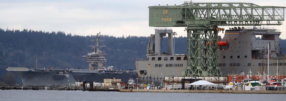 The Hammerhead crane looms in the foreground as the USS Nimitz leaves Naval Base Kitsap-Bremerton on Monday.