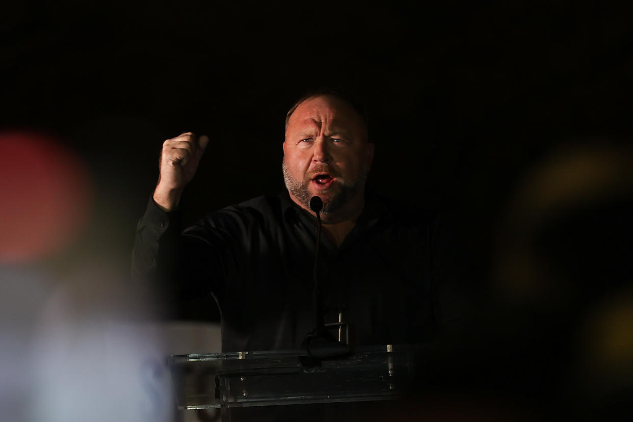 Alex Jones makes his point, raising his fist in the dark.