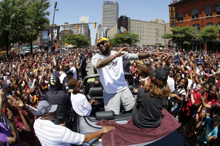 Cleveland Cavaliers' LeBron James, center, stands in the back of a Rolls Royce as it makes its way through the crowd in downtown Cleveland, in celebration of the team's NBA championship. ( Photo: Gene J. Puskar/AP)