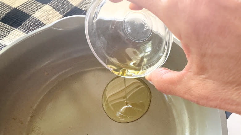 hand adding oil to pan