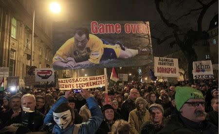 Protesters hold a poster with the picture of Hungarian Prime Minister Viktor Orban and the text 'Game Over' as they take part in a demonstration of protest, called by civil groups, against austerity measures, corruption and general economic hardship, in Budapest, December 16, 2014. REUTERS/Bernadett Szabo