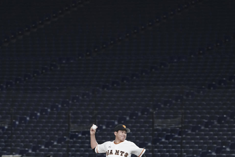 Tomoyuki Sugano of the Yomiuri Giants pitches with a backdrop of empty stands during play in a preseason baseball game between the Yomiuri Giants and the Yakult Swallows at Tokyo Dome in Tokyo Saturday, Feb. 29, 2020. Japan's professional baseball league said Thursday it will play its 72 remaining preseason games in empty stadiums because of the threat of the spreading coronavirus. (AP Photo/Eugene Hoshiko)