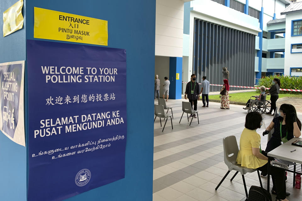 Voters observe social distancing while lining up at the Dunearn Secondary School polling station in Singapore Friday, July 10, 2020. Wearing masks and plastic gloves, Singaporeans began voting in a general election that is expected to return Prime Minister Lee Hsien Loong's long-ruling party to power. (AP Photo/Royston Chan)