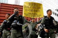 A police officer holds a banner with a warning as people gather for a protest in Hong Kong