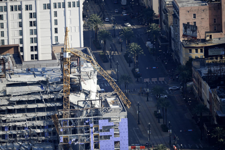 One of two large cranes from the Hard Rock Hotel construction collapse is seen hanging over the edge above Canal Street in this aerial photo, after being detonated for implosion in New Orleans, Sunday, Oct. 20, 2019. (AP Photo/Gerald Herbert)