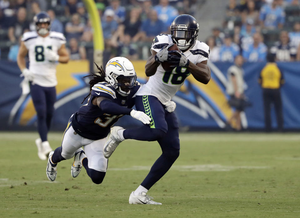 Seattle Seahawks wide receiver Jaron Brown (18) runs after a catch as Los Angeles Chargers defensive back Jahleel Addae reaches for the tackle during the first half of an NFL preseason football game Saturday, Aug. 18, 2018, in Carson, Calif. (AP Photo/Gregory Bull )