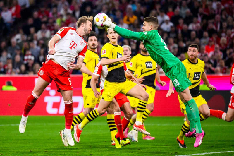 Munich's Harry Kane (L) in action against Dortmund's goalkeeper Alexander Meyer during the German Bundesliga soccer match between Bayern Munich and Borussia Dortmund at the Allianz Arena. Tom Weller/dpa