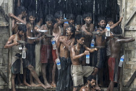 Migrants, who were found at sea on a boat, collect rainwater during a heavy rain fall at a temporary refuge camp near Kanyin Chaung jetty, outside Maungdaw township, northern Rakhine state, Myanmar June 4, 2015. REUTERS/Soe Zeya Tun