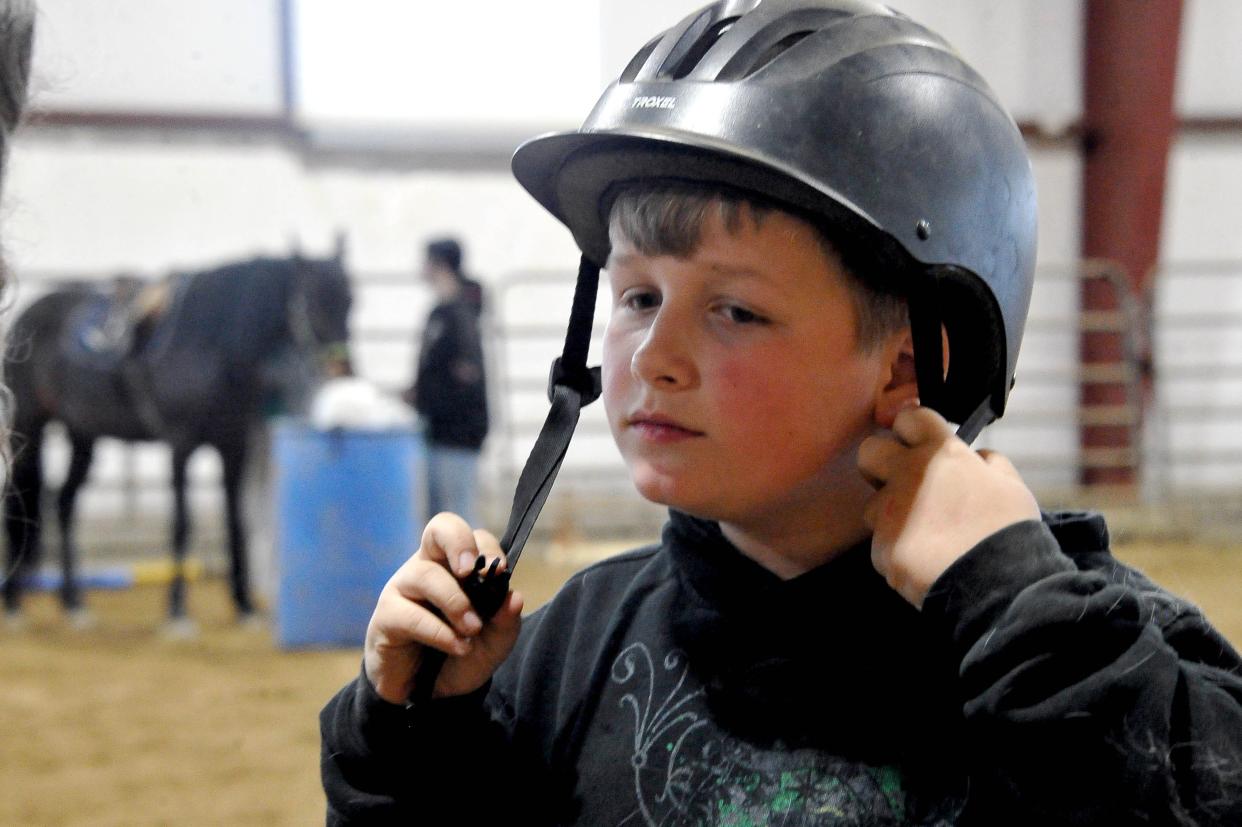 Landon Vierheller puts a helmet on and is ready to ride at Stirrup Courage. Sessions include activities, games and challenges that gradually build up their skills and confidence.