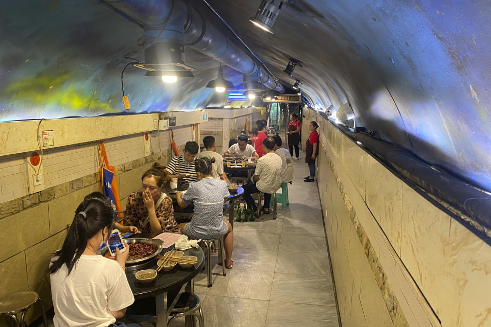 Customers eat hotpot in a hotpot restaurant located in a converted WWII-era air raid shelter in southwestern China's Chongqing Municipality, Saturday, Aug. 20, 2022. The city of Chongqing, dubbed one of China's four "furnace" cities, is known for both soaring temperatures and spicy cuisine - notably its hotpot, a peppery bubbling tabletop broth into which diners dunk bite-size pieces of food to cook and eat. (AP Photo/Mark Schiefelbein)