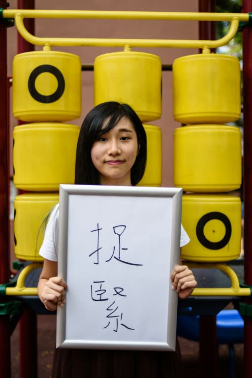 Hong Kong student and pro-democracy activist Chau Ho-oi holds a board upon which she wrote Chinese characters to sum up her Hong Kong. It says: 'To hold onto.'