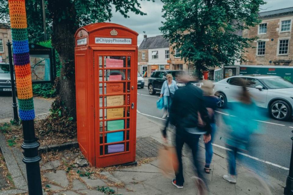 A red phone box is decorated in Pride colours