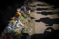 FILE - Visitors cast shadows at a memorial to the victims of the Astroworld concert in Houston on Sunday, Nov. 7, 2021. Several families of the 10 people who died from injuries in the crush of fans at the Astroworld festival have turned down an offer by headliner Travis Scott to pay for their loved ones’ funeral costs. (AP Photo/Robert Bumsted, File)