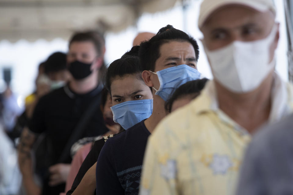 Tourists gather at Immigration Bureau to extend their visa in Bangkok, Thailand, Friday, March 27, 2020. Tourists across Asia are finding their dream vacations have turned into travel nightmares as airlines cancel flights and countries close their borders in the fight against the coronavirus pandemic. (AP Photo/Sakchai Lalit)