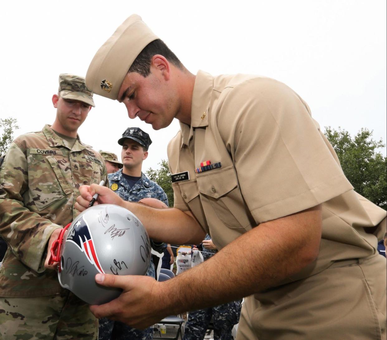Joe Cardona autographs a helmet for military fans at Jacksonville’s EverBank Field in 2017.