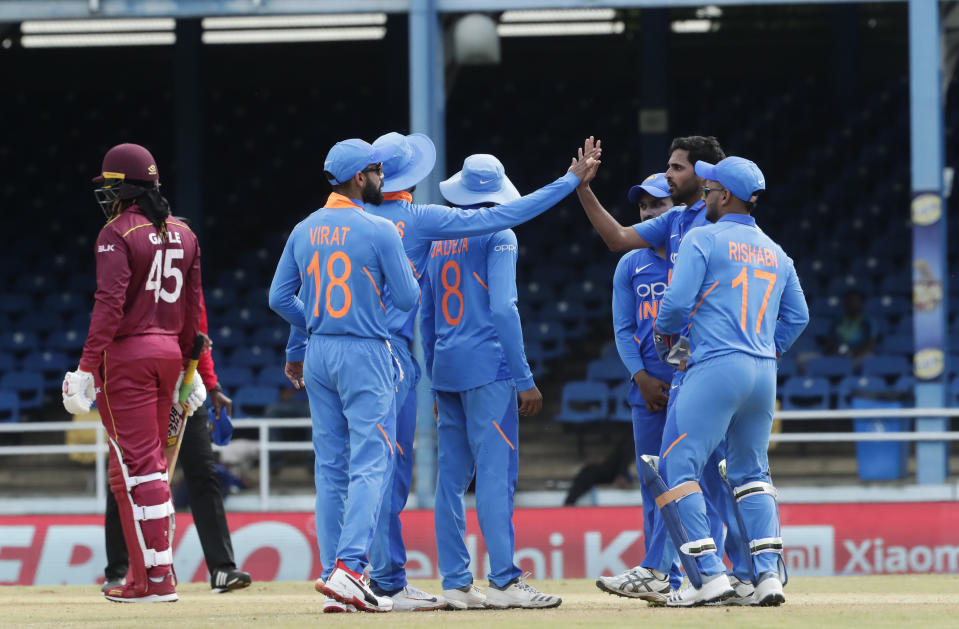 India's bowler Bhuvneshwar Kumar, second right, is congratulated by teammates after taking the wicket of West Indies' Chris Gayle, left, who was trapped LBW for a 11 runs, during their second One-Day International cricket match in Port of Spain, Trinidad, Sunday, Aug. 11, 2019. (AP Photo/Arnulfo Franco)