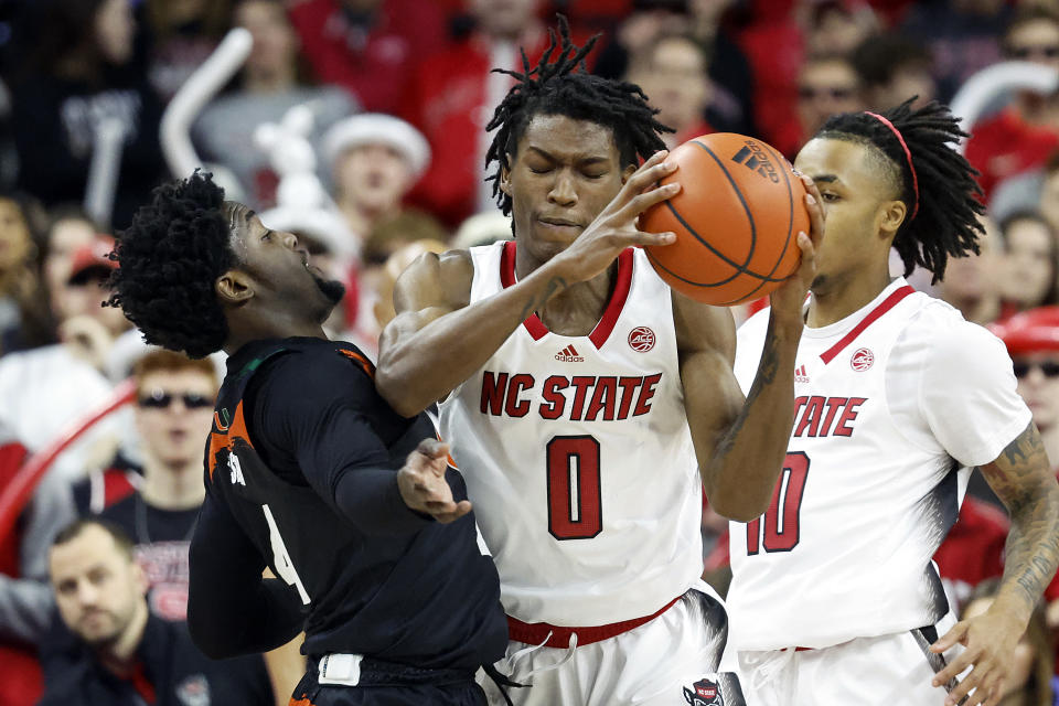 North Carolina State's Terquavion Smith (0) struggles against Miami's Bensley Joseph (4) during the first half of an NCAA college basketball game in Raleigh, N.C., Saturday, Jan. 14, 2023. (AP Photo/Karl B DeBlaker)