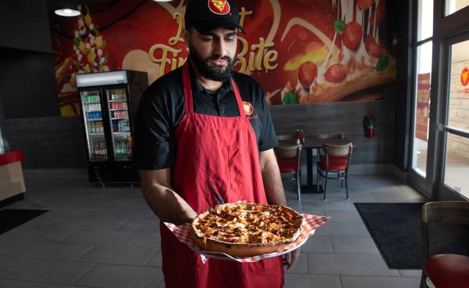 Anmol Sekhon delivers a deep-dish pizza at Pizza Twist in Modesto, Calif., Thursday, April 6, 2023.