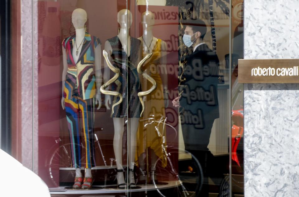 A shop assistant wears a sanitary mask in a clothing shop in Milan, Italy, Monday, Feb. 24, 2020. Police manned checkpoints around quarantined towns in Italy's north on Monday as authorities sought to contain cases of COVID-19 virus that have made Italy the focal point of the outbreak in Europe and fears of its cross-border spread. At least 190 people in Italy's north have tested positive for the virus and four people have died, including an 84-year-old man who died overnight in Bergamo, the Lombardy regional government reported. (AP Photo/Luca Bruno)