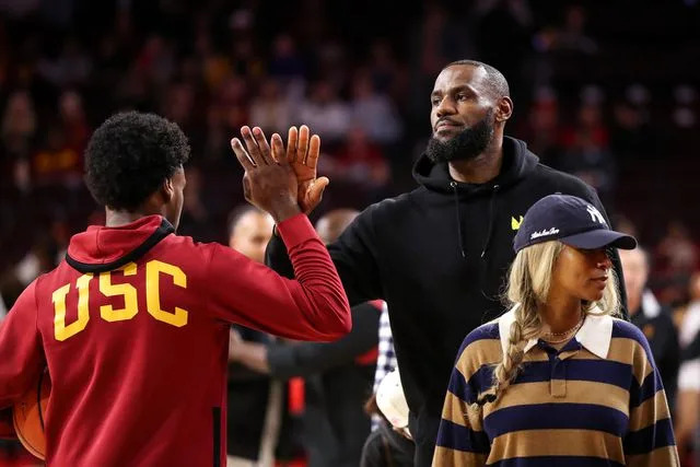 <p>Meg Oliphant/Getty </p> Bronny James #6 of the USC Trojans greets his dad, LeBron James of the Los Angeles Lakers, before the game against the Stanford Cardinal at Galen Center on January 06, 2024 in Los Angeles, California.