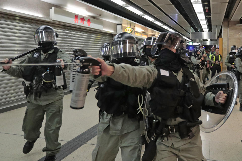 A riot police fires pepper spray toward people at a shopping mall in Hong Kong, Sunday, Nov. 3, 2019. Riot police stormed several malls in Hong Kong on Sunday in a move to thwart more pro-democracy protests, as the city's leader heads to Beijing for talks on deepening economic integration between the semi-autonomous Chinese territory and mainland China. (AP Photo/Dita Alangkara)