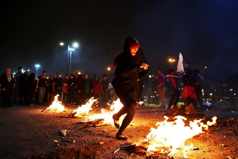 In this picture taken on Tuesday, March 18, 2014, an Iranian woman jumps over bonfires during a celebration, known as “Chaharshanbe Souri,” or Wednesday Feast, marking the eve of the last Wednesday of the solar Persian year, in Pardisan park, Tehran, Iran. The festival has been frowned upon by hard-liners since the 1979 Islamic revolution because they consider it a symbol of Zoroastrianism, one of Iran’s ancient religions of Iranians. They say it goes against Islamic traditions. (AP Photo/Ebrahim Noroozi)