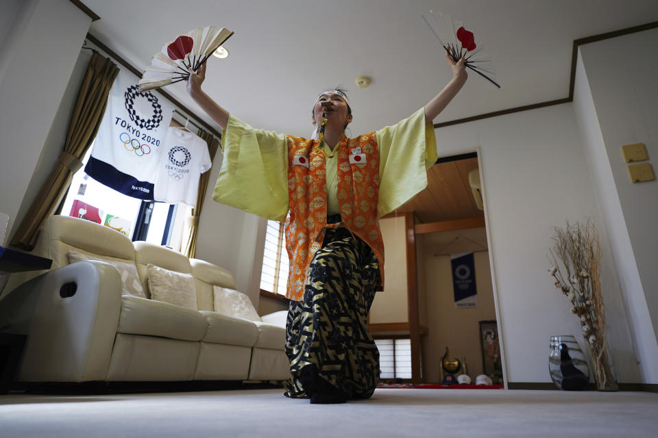 Olympic fan Kyoko Ishikawa shows her cheering at her home Saturday, April 10, 2021, in Tokyo. Ishikawa, president of an IT company, has attended every Summer Olympics since Barcelona in 1992, becoming famous as an unofficial "International Olympic Cheerleader." She relishes joining in with fans from everywhere to cheer for their athletes. (AP Photo/Eugene Hoshiko)