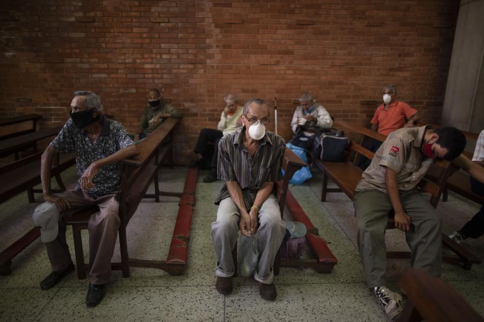 People, wearing protective face masks as a precaution against the spread of the new coronavirus, wait to receive a free meal at a church in The Cemetery neighborhood of Caracas, Venezuela, Friday, May 22, 2020. One in every three people faced hunger last year in Venezuela, according to the food agency's 2019 study.church has increased in quarantine. (AP Photo/Ariana Cubillos)