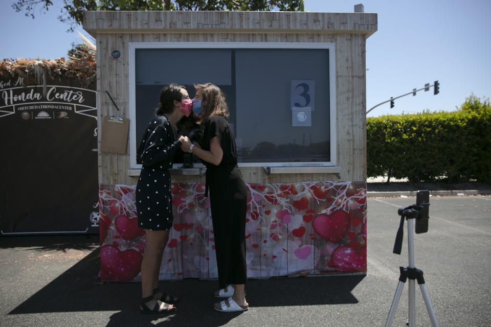 Kelly Miller, left, and Hana Stevenson kiss during their marriage service in a parking lot in Anaheim, Calif., Tuesday, May 26, 2020. Started in mid-April, the pop-up site has been serving more than 100 couples a day. (AP Photo/Jae C. Hong)